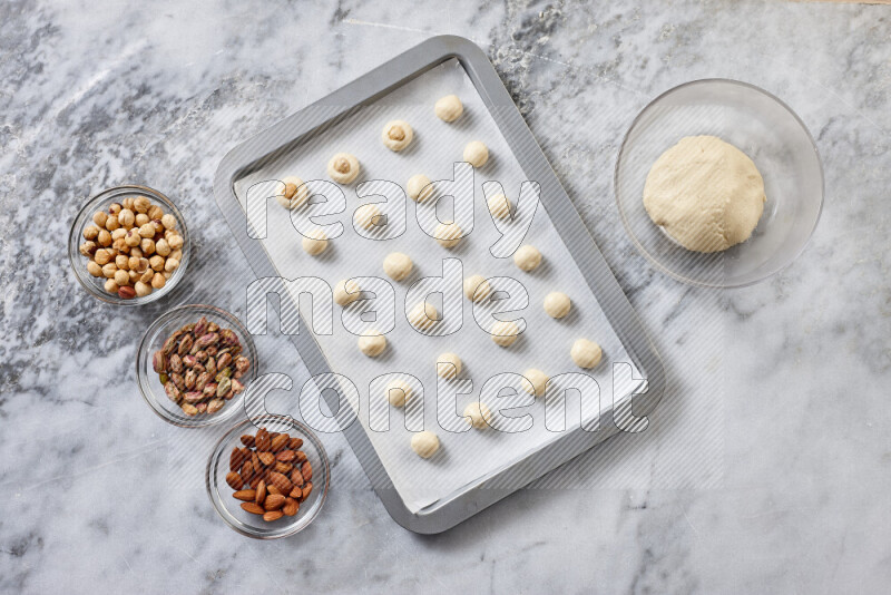 Ghoriba step by step with its ingredient, flour, powdered sugar, ghee and nuts on grey marble background