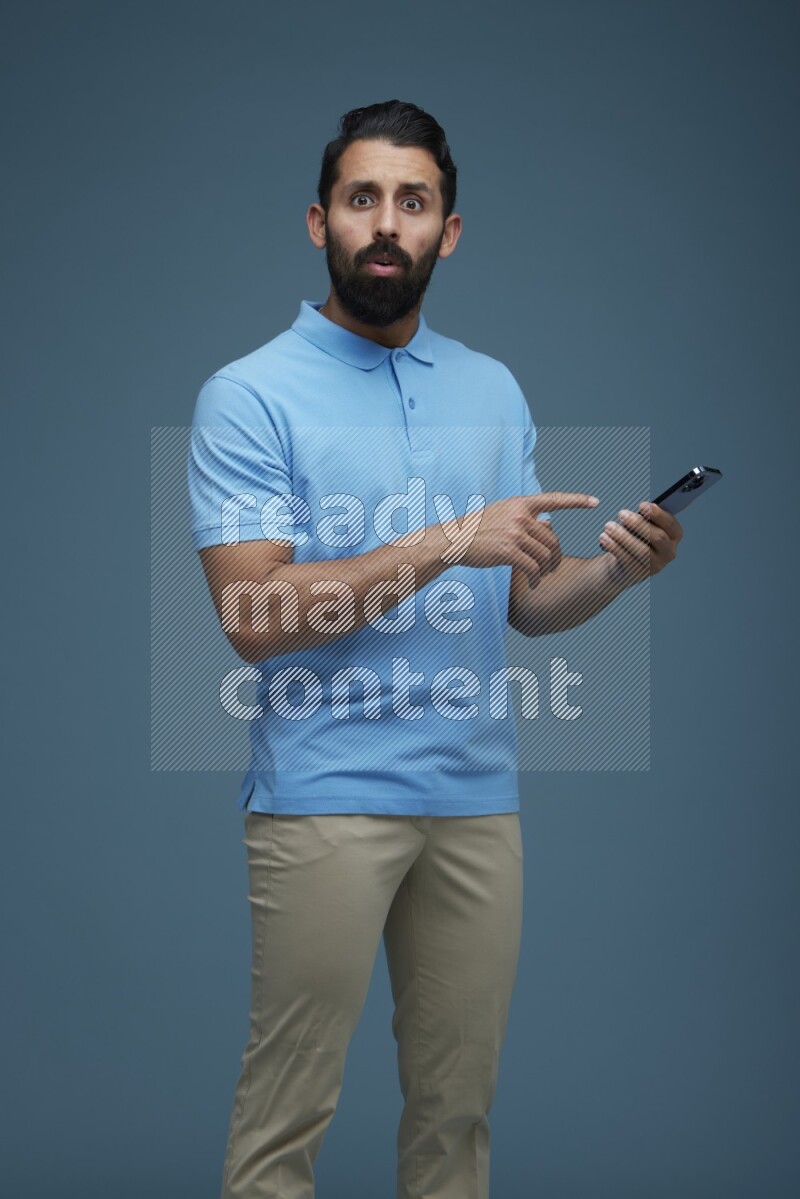 Man posing with a phone in a blue background wearing a Blue shirt