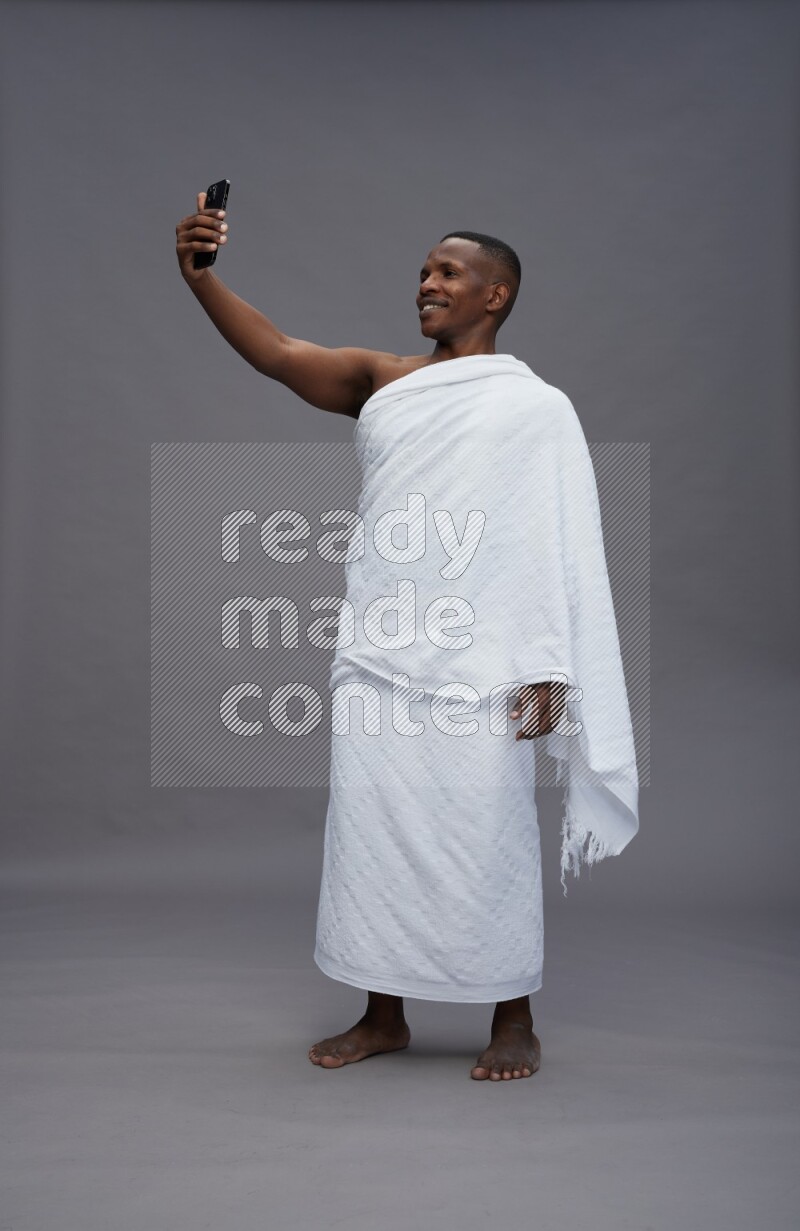 A man wearing Ehram Standing taking selfie on gray background