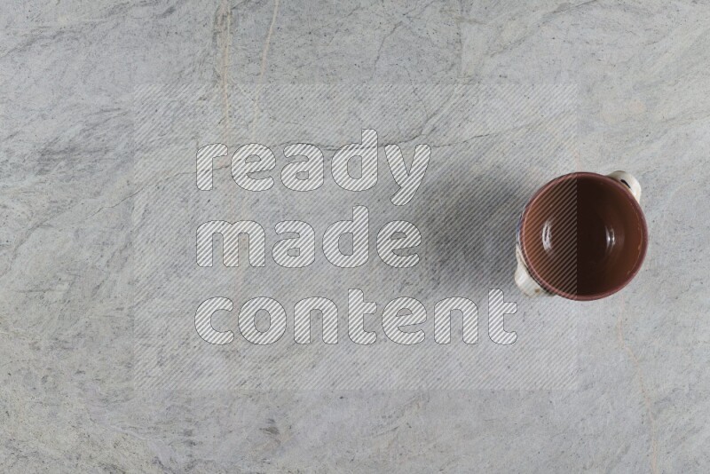 إناء فخاري متعدد الألوان مع غطائه على خلفية من الرخام الرمادي