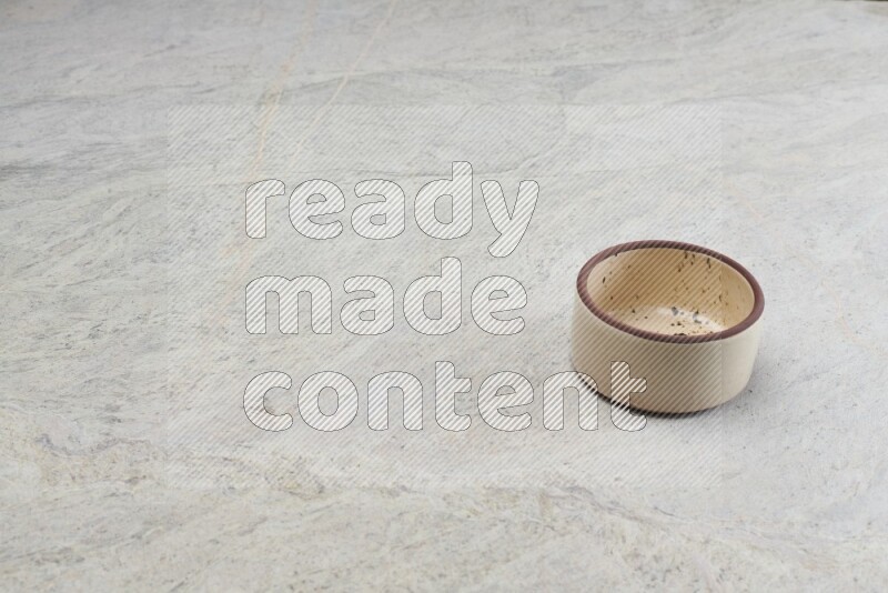 A small beige pottery bowl on grey marble background