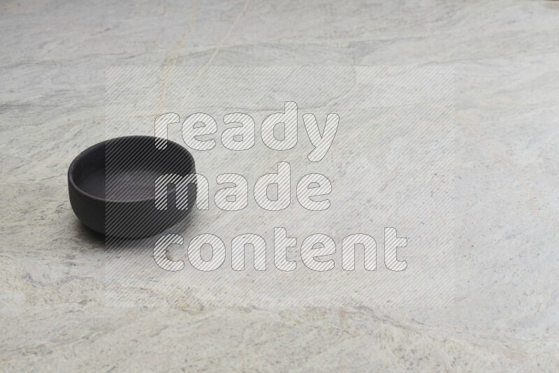 A black pottery bowl on grey marble background
