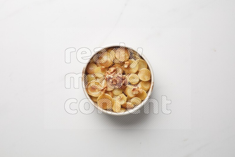 Top-view shot of walnut cereal pancakes in a round bowl on white background