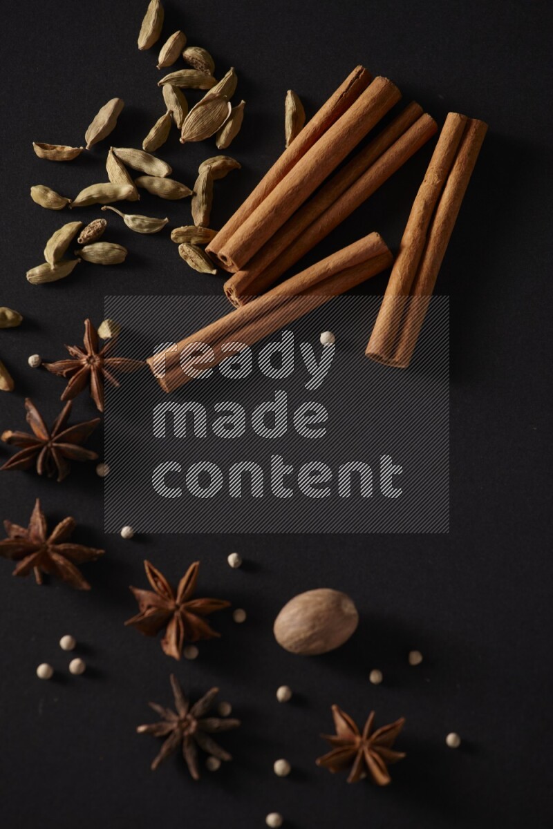 Cinnamon sticks, cardamom, star anise, nutmeg and white peppers on a black background