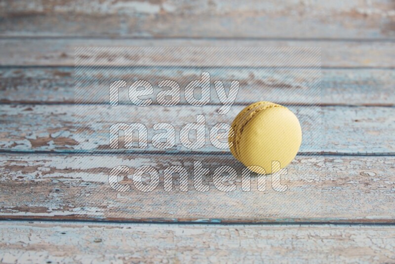 45º Shot of Yellow Lime macaron on light blue wooden background