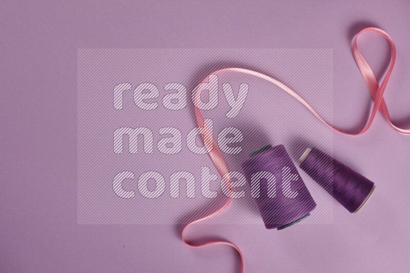 A pink and purple collection of sewing and tailoring tools arranged on a purple background