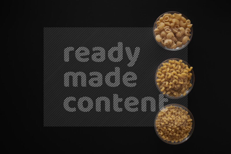 Different pasta types in 3 glass bowls on black background