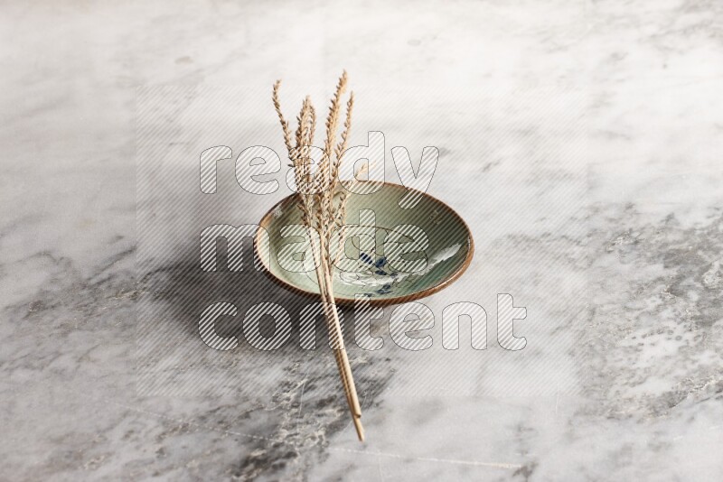 Wheat stalks on decorative pottery plate on grey marble background