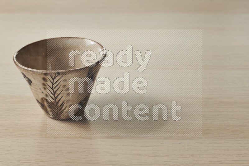 A decorative pottery bowl on light wooden background