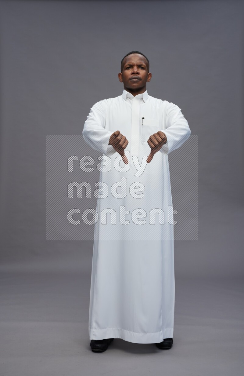 Saudi man wearing thob standing interacting with the camera on gray background