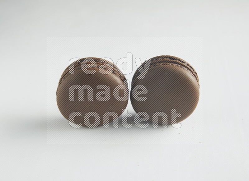 45º Shot of two Brown Dark Chocolate macarons on white background