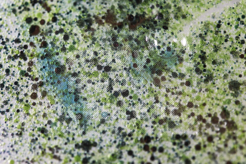 لقطات مقربة لقطرات ألوان مائية خضراء وزرقاء على سطح الزيت على خلفية بيضاء