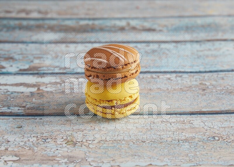 45º Shot of of two assorted Brown Irish Cream, and Yellow Lemon macarons on light blue background