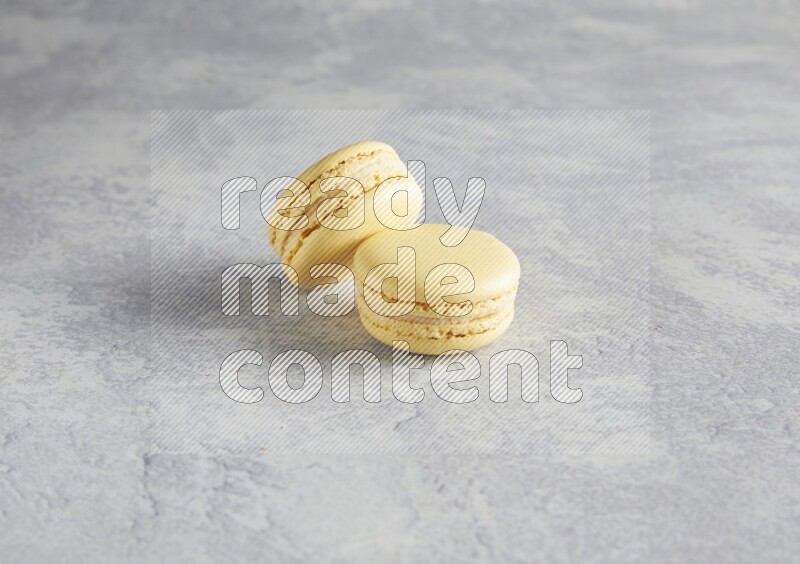 45º Shot of two Yellow Vanilla macarons  on white  marble background