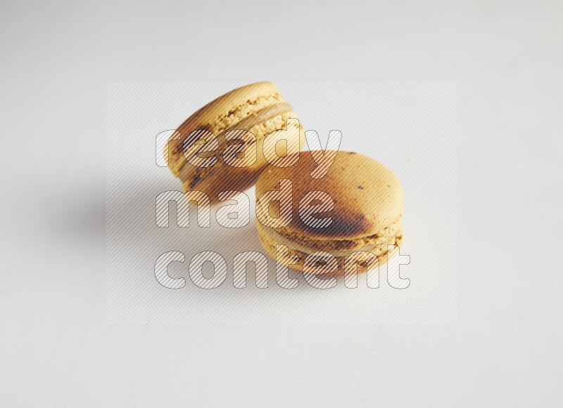 45º Shot of two Yellow Crème Brulée macarons on white background