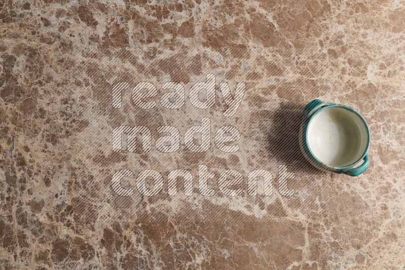 A multicolored pottery bowl on beige marble background