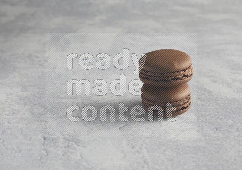 45º Shot of two Brown Dark Chocolate macarons  on white  marble background