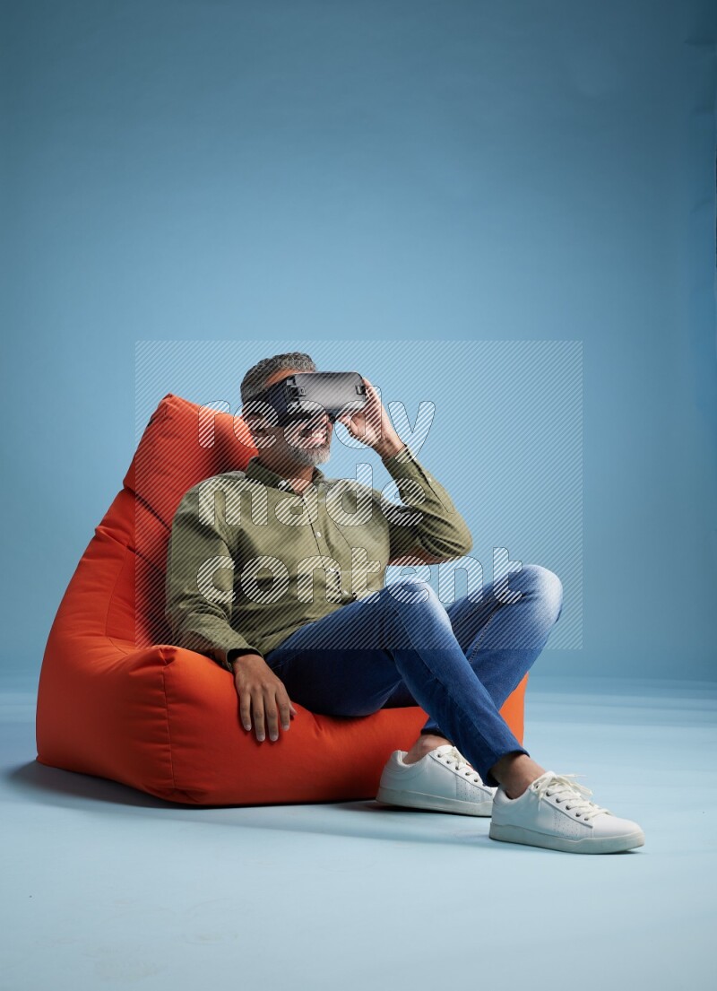 A man sitting on an orange beanbag and gaming with VR
