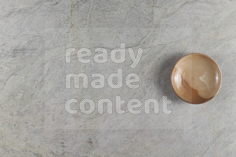 A beige pottery plate on grey marble background