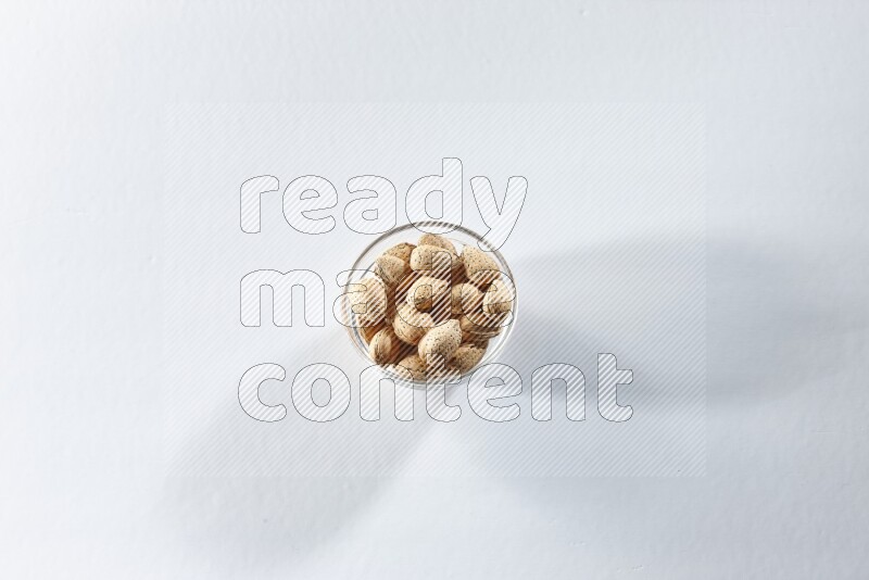 A glass bowl full of almonds on a white background in different angles