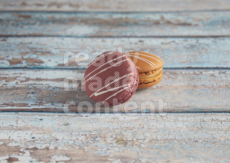 45º Shot of of two assorted Brown Irish Cream, and Red Poppy Flower macarons  on light blue background