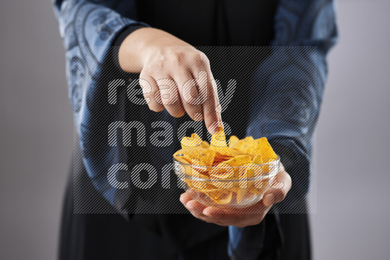 Woman in abaya holding different kinds of snacks in different positions