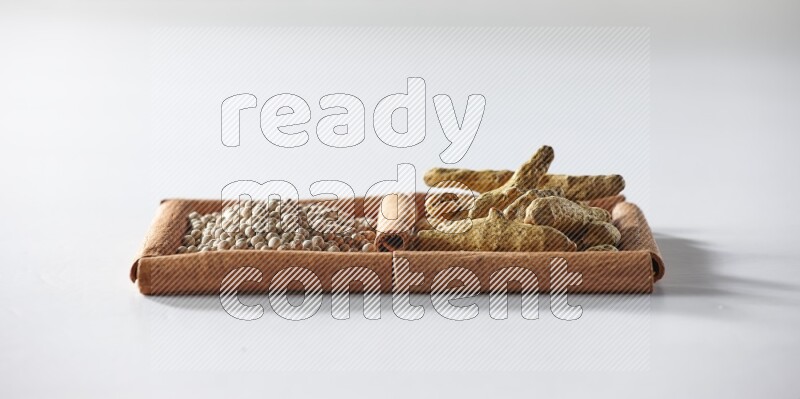 2 squares of cinnamon sticks full of white pepper and turmeric fingers on white flooring