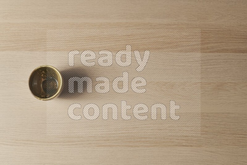 كأس فخاري متعدد الألوان على خلفية خشبية فاتحة