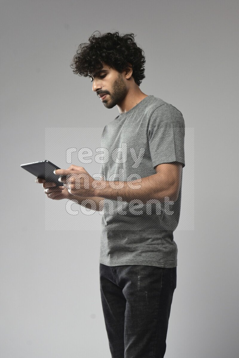 A man wearing casual standing and gaming on a tablet on white background