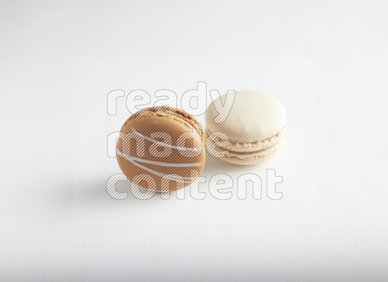 45º Shot of of two assorted Brown Irish Cream, and White Caramel fleur de sel macarons on white background