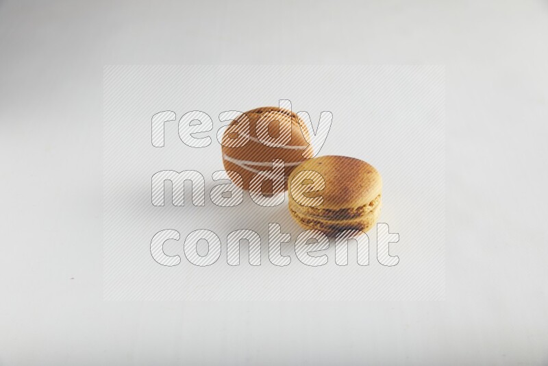 45º Shot of of two assorted Brown Irish Cream, and Yellow Crème Brulée macarons on white background