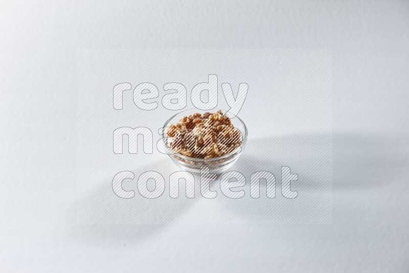 A glass bowl full of peeled walnuts on a white background in different angles