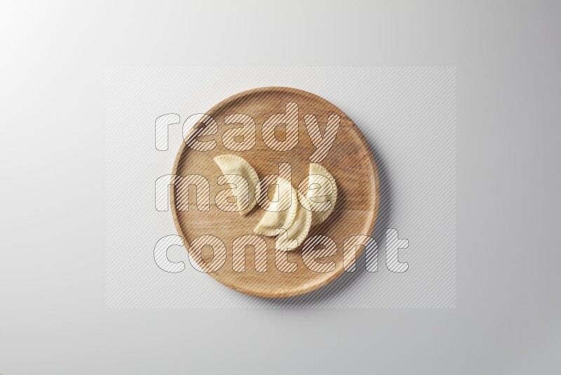 Four Sambosas on a wooden round plate on a white background