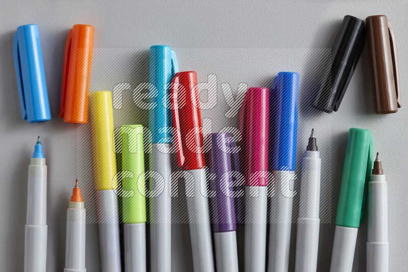 An arrangement of coloring pens in different colors on grey background