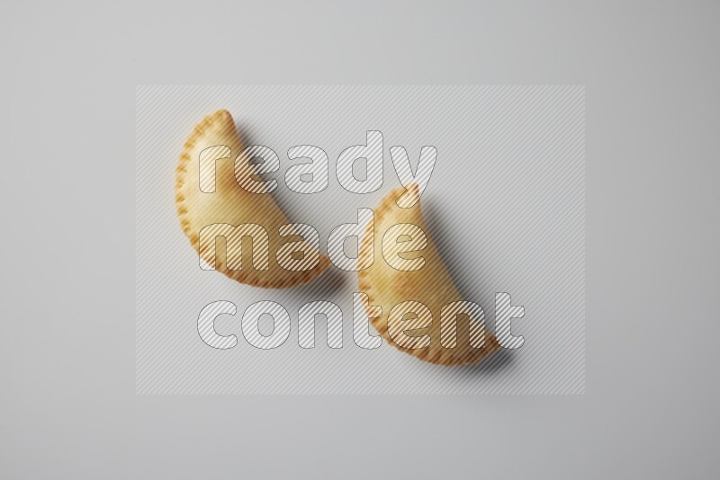 Two fried sambosa from a top angle on a white background