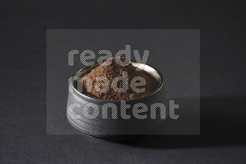 وعاء فخاري أسود ممتلئ ببودرة القرنفل علي خلفية سوداء