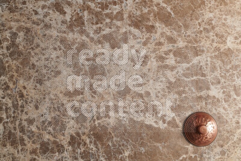 A small copper pot on beige marble background
