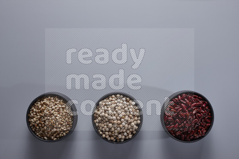 Legumes in pottery bowls on light grey background
