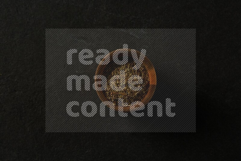 wooden round sauce bowl filled with herbs on grey textured countertop