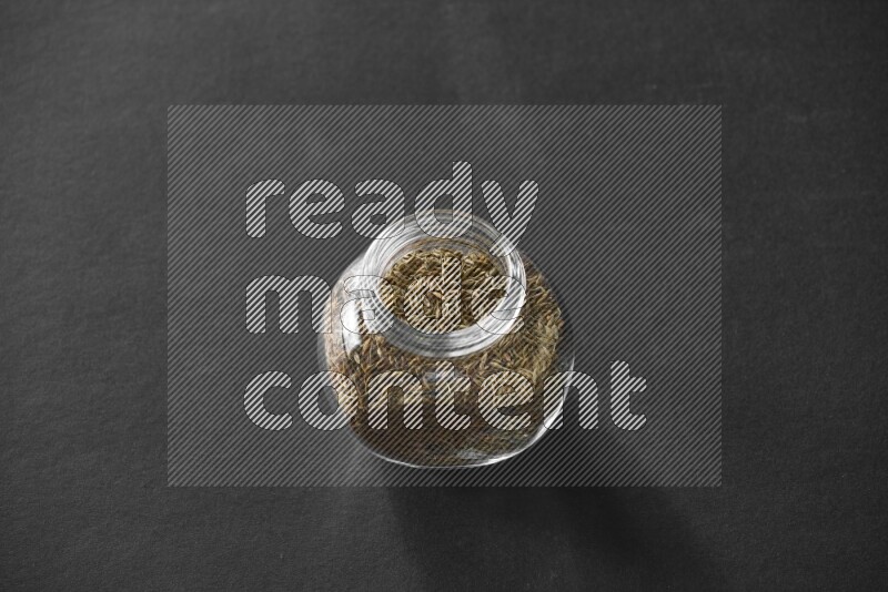 كمون في وعاء زجاجي علي خلفية سوداء