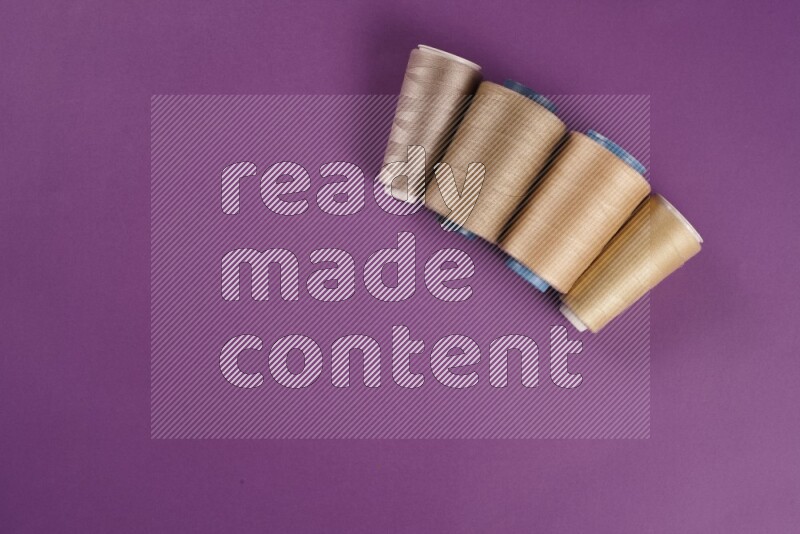 A beige collection of sewing and tailoring tools arranged on a purple background