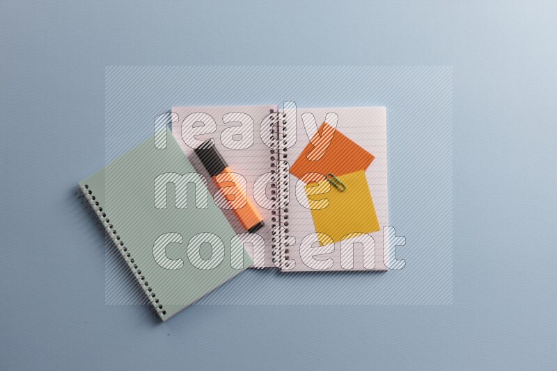 A blue notebook with different school supplies on blue background
