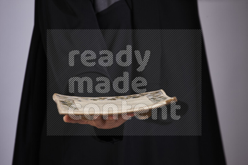 امرأة ترتدي عباءة سوداء تحمل أدوات فخارية مختلفة في أوضاع متعددة