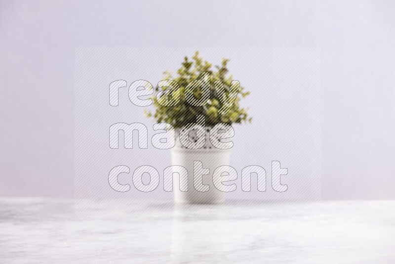 Artificial plant in white decorative pot on grey marble background