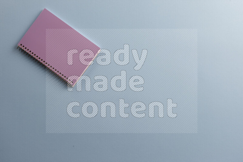 A purple notebook with different school supplies on blue background