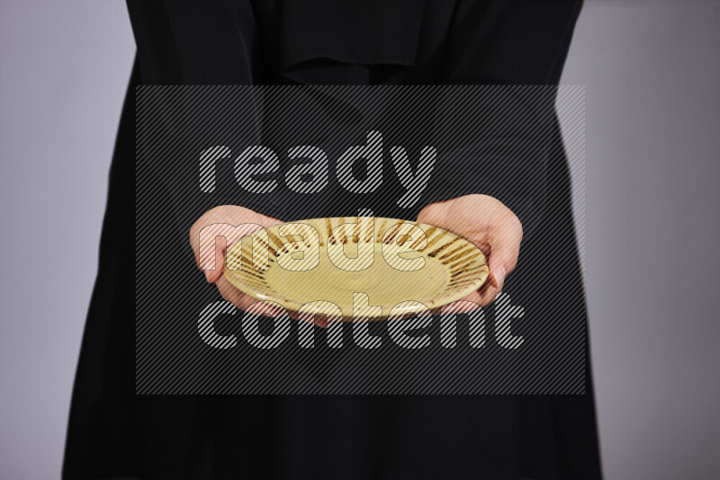 A woman in black abaya holding different pottery essentials in different positions