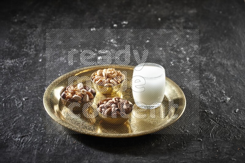 مكسرات في أطباق معدنية مع السوبيا على صينية علي خلفية سوداء