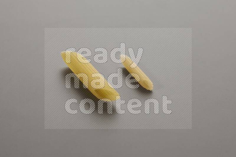 Penne pasta with other types of pasta on grey background