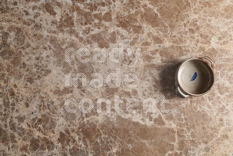 A multicolored pottery bowl on beige marble background