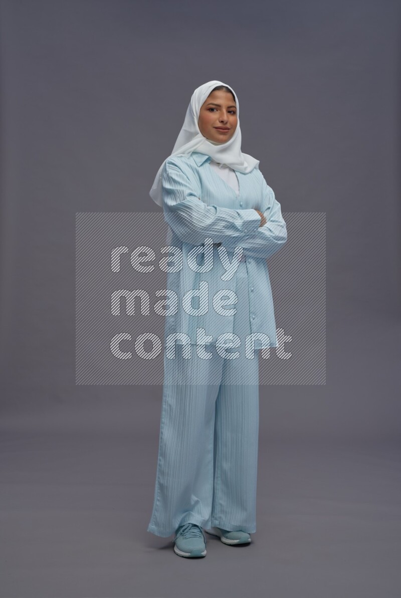 Saudi woman wearing hijab clothes standing with crossed arms on gray background